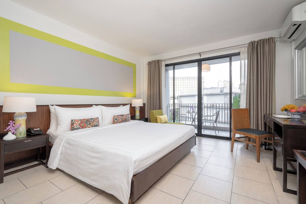 Une chambre d’hôtel avec un grand lit, un bureau, une chaise et un balcon offrant une vue sur la ville.