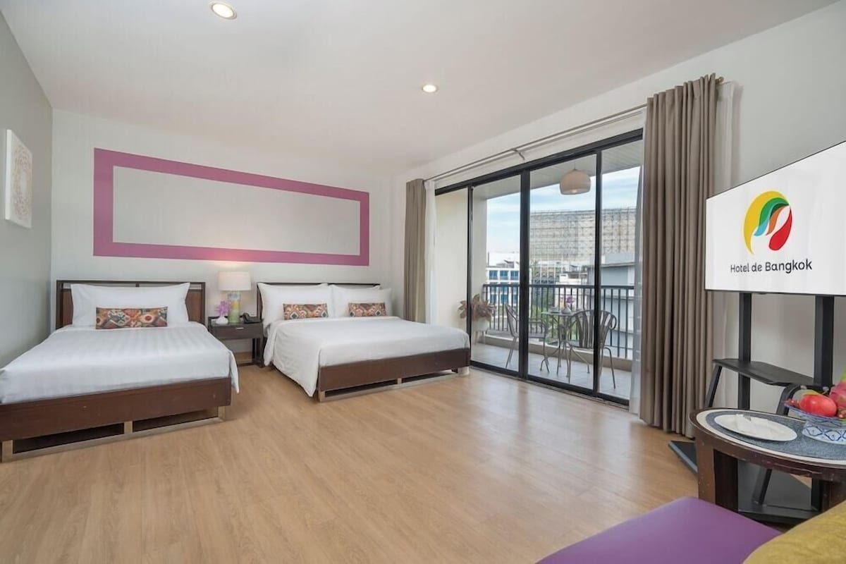Ein Hotelzimmer mit zwei Betten, einem Balkon und Blick sowie einem Esstisch mit Teller und Obstschale.