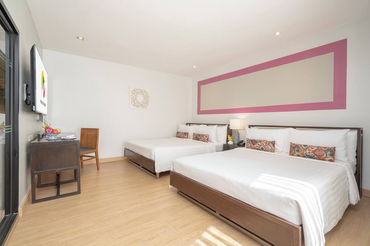 Une chambre d’hôtel avec deux lits simples, un bureau, une chaise et un téléviseur.