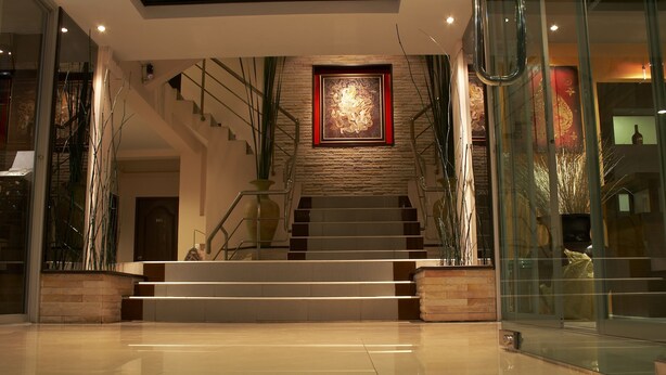 A modern staircase with glass railings and a framed artwork above. - Grand Pinnacle (Bangkok)