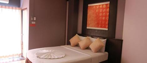 A hotel room with a large bed, a headboard with a decorative panel, and a window with curtains.