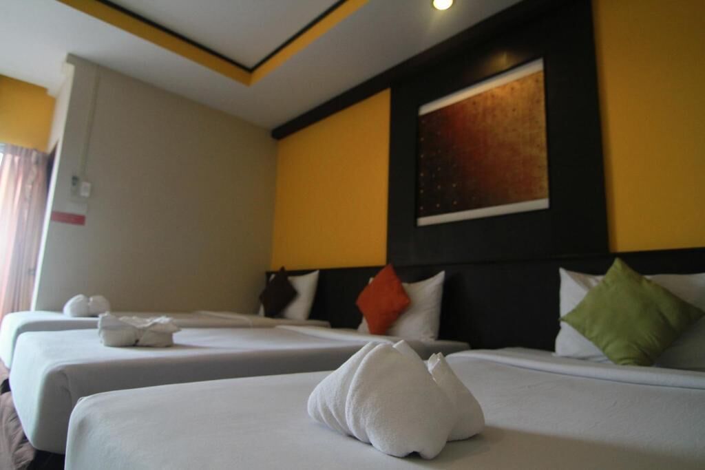 A hotel room with two beds, each with neatly folded towels.