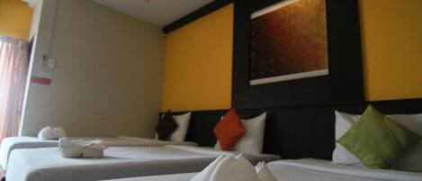 A hotel room with two beds, each with neatly folded towels.