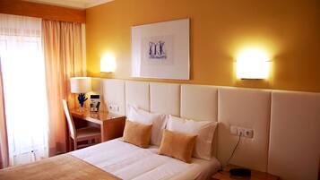 Habitación de hotel con cama, mesita de noche, lámpara y un cuadro en la pared.
