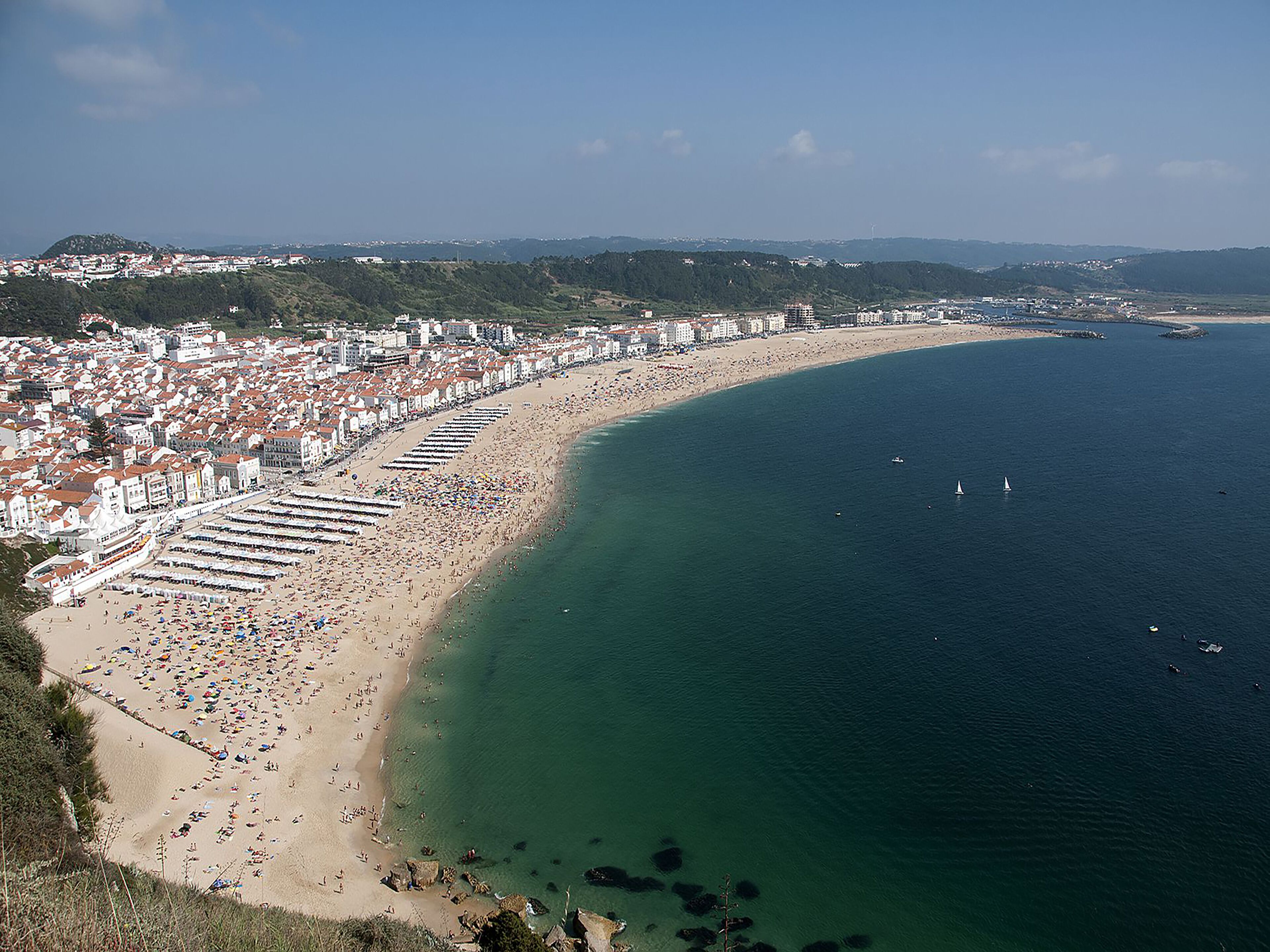 Une ville côtière dotée d’un long littoral bordé de bâtiments blancs et d’une plage de sable.