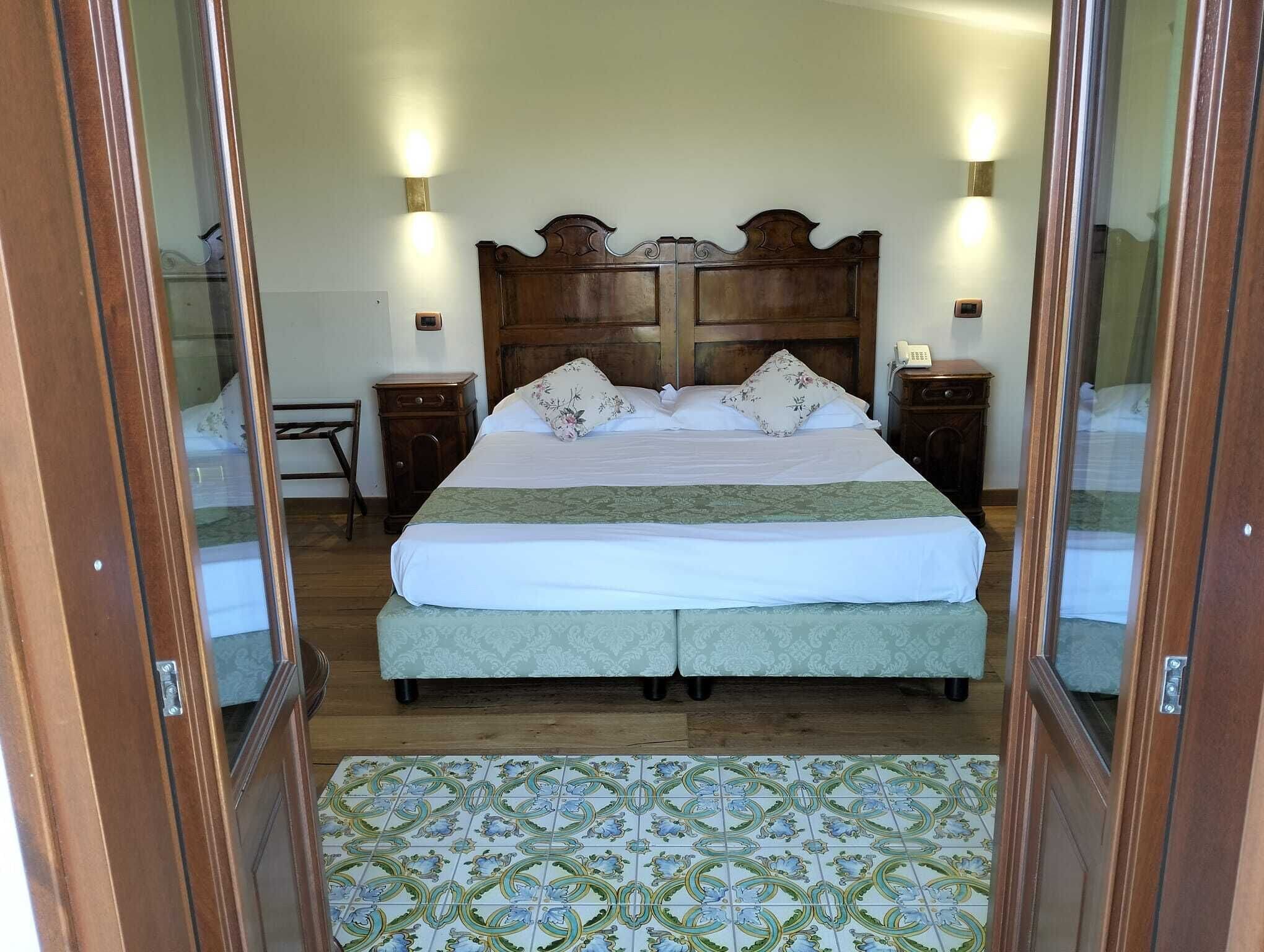 Un dormitorio con una cama grande, dos mesitas de noche, un cabecero de madera y un suelo estampado.