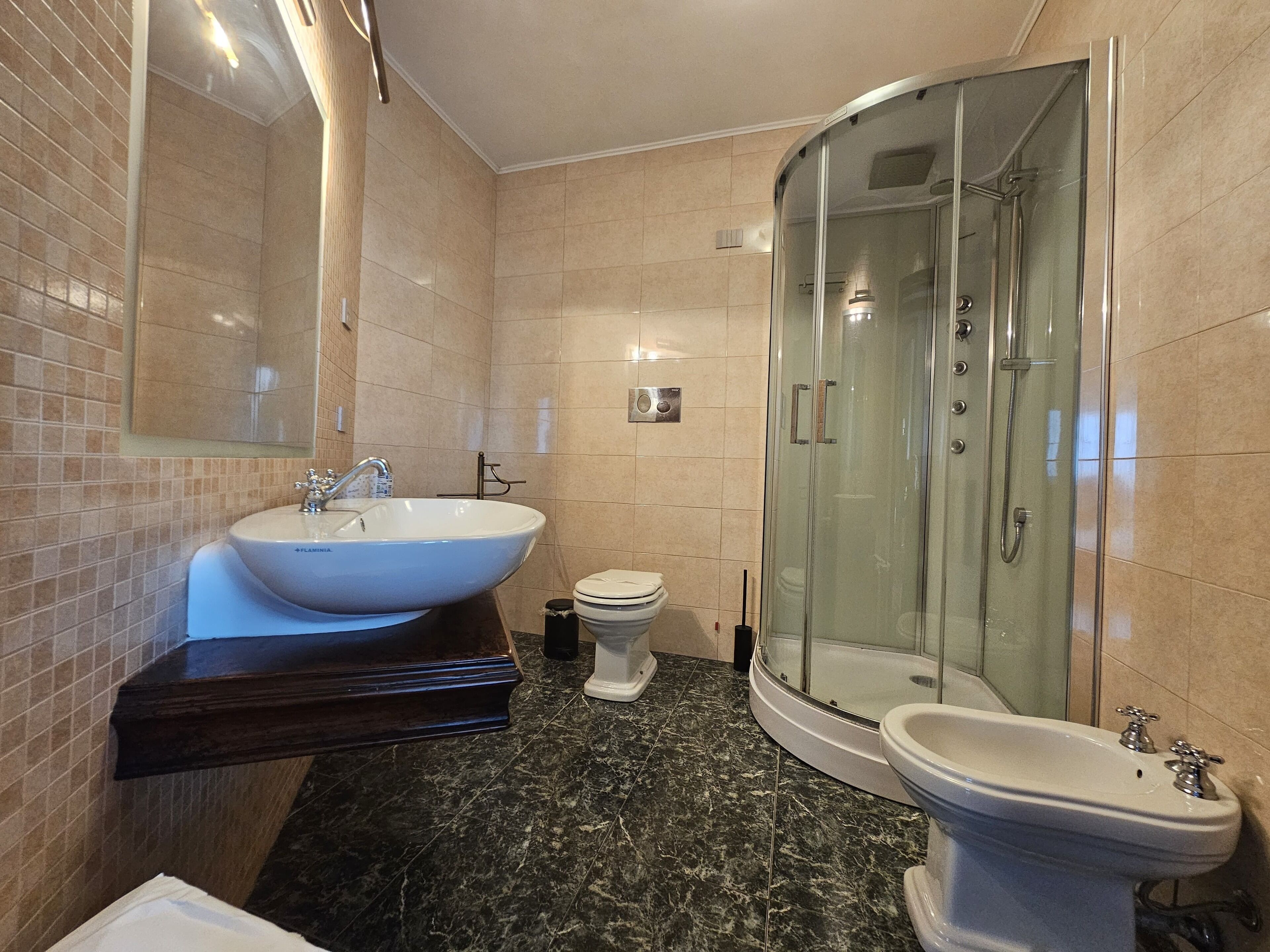 Une salle de bain moderne dotée d’un grand lavabo, de toilettes, d’un bidet et d’une douche à parois de verre.