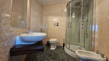 Une salle de bain moderne dotée d’un grand lavabo, de toilettes, d’un bidet et d’une douche à parois de verre.