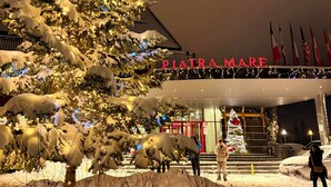 Un árbol cubierto de nieve frente a un edificio con un letrero que dice 'PIATRA MARE'.