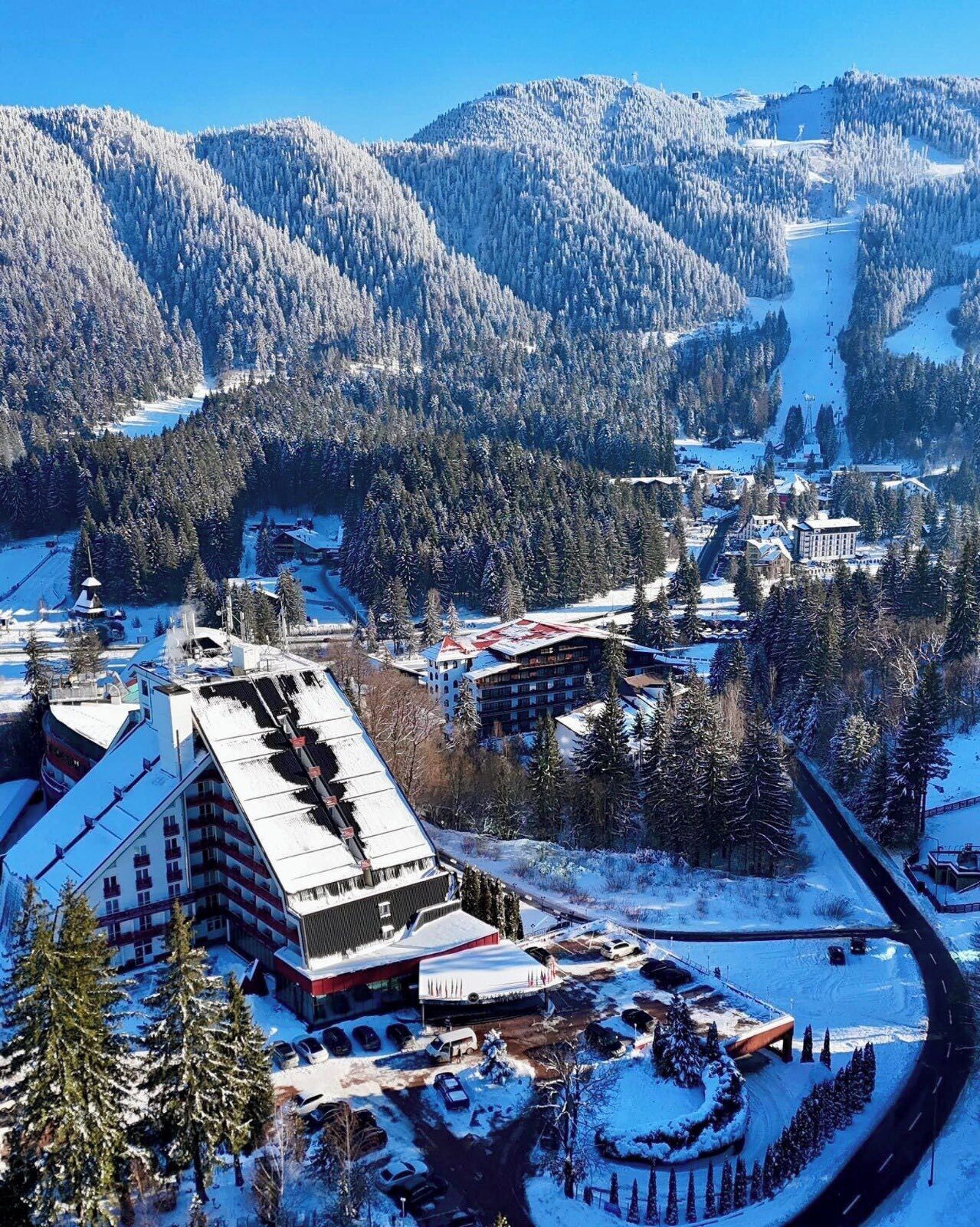 A snow-covered mountain town with a prominent building featuring a sloped roof and multiple windows.