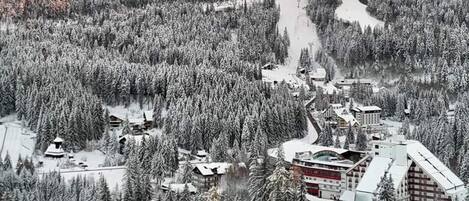 A snow-covered mountainous area with a ski resort, including buildings and ski lifts.