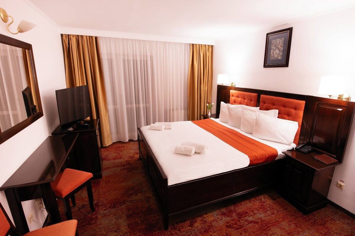 Une chambre d’hôtel avec un grand lit, un bureau avec une chaise, une télévision et un tableau encadré au mur.