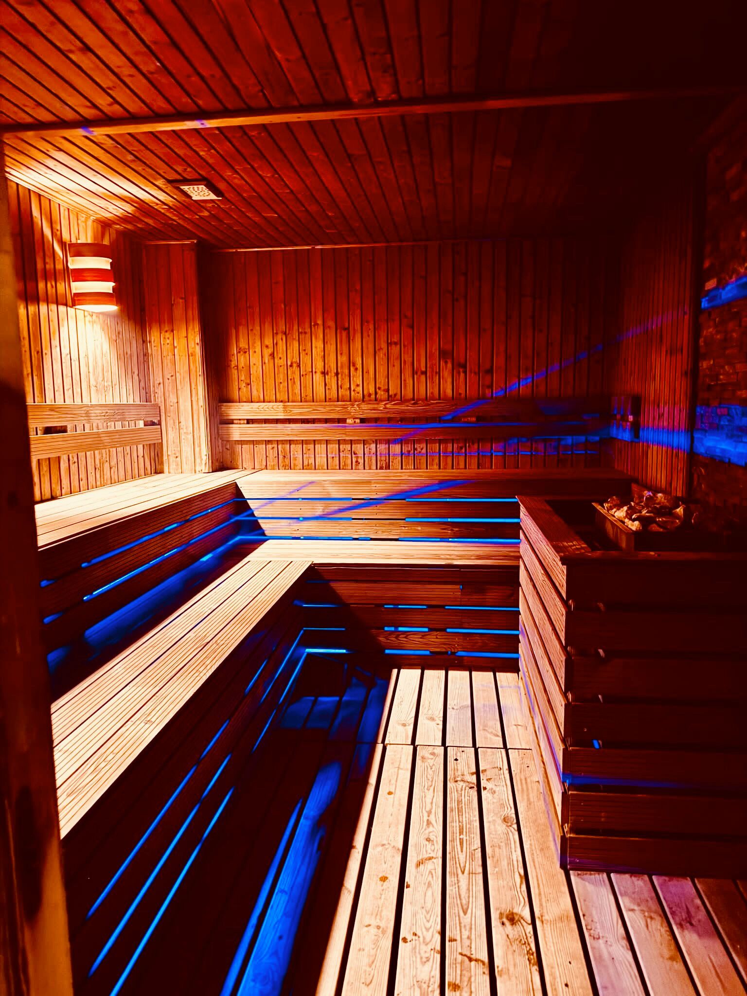A sauna with wooden benches and a stone wall.