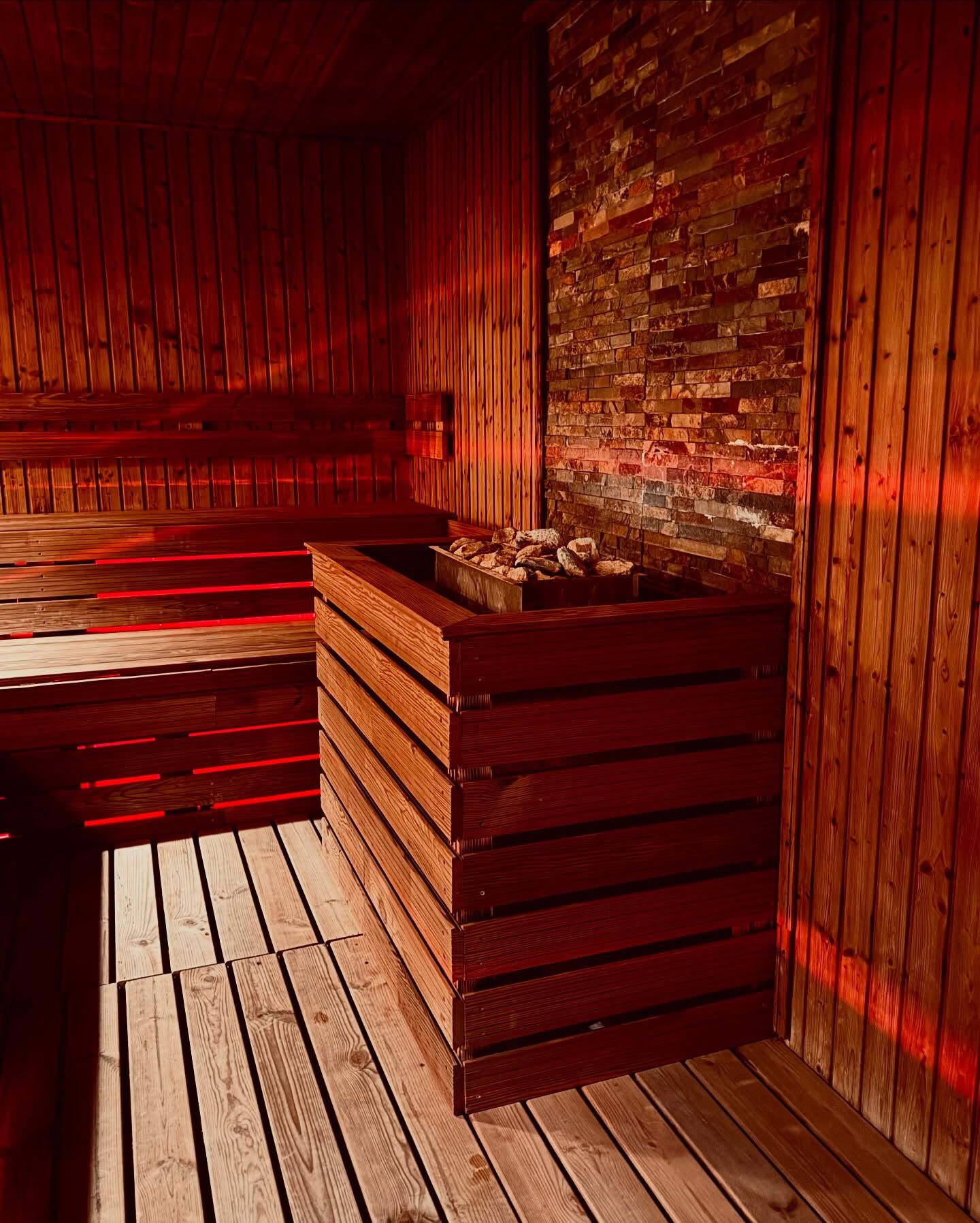 A sauna room with wooden benches and a brick wall.