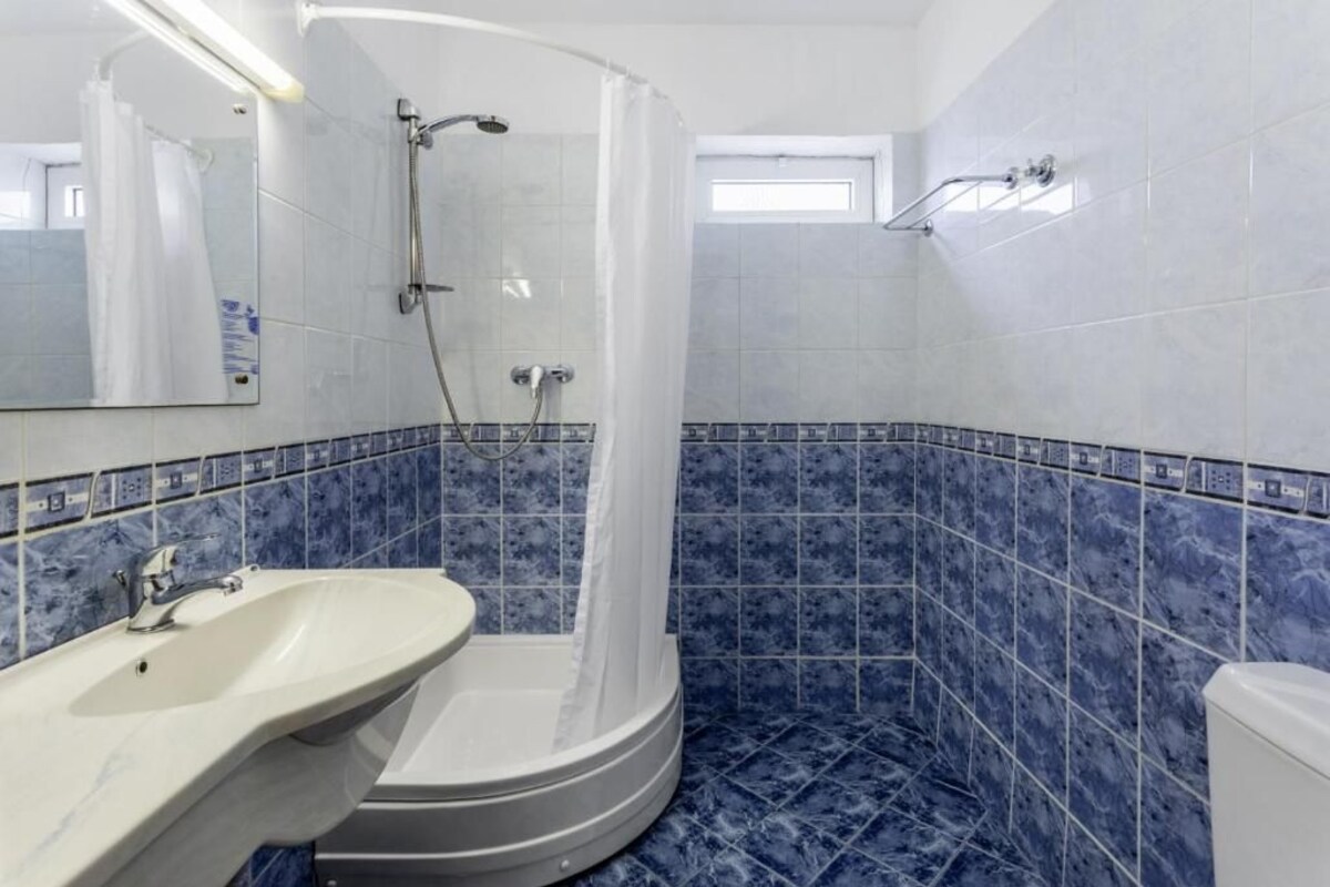 Un baño con ducha, lavamanos, inodoro y espejo.