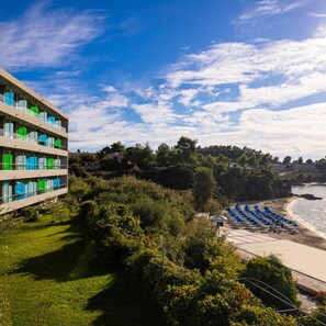 A coastal hotel with a view of the beach, a grassy area, and a building with multiple balconies. - Mediterranee (KEFALONIA)