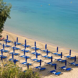 A beach with rows of blue sun loungers and umbrellas, clear blue water, and a sandy shore. - Mediterranee (KEFALONIA)