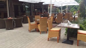An outdoor cafe area with wicker furniture and umbrellas. - Hotel Bahami Residence (Sunny Beach)