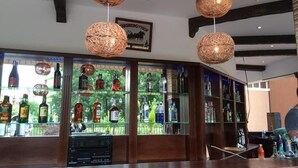 A bar area with wicker pendant lights, a glass display of liquor bottles, and a framed picture on the wall. - Hotel Bahami Residence (Sunny Beach)