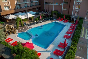 Una piscina al aire libre, sombrillas, tumbonas