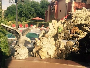 A pool area with a rock formation and a sculpture of an eagle. - Hotel Bahami Residence (Sunny Beach)
