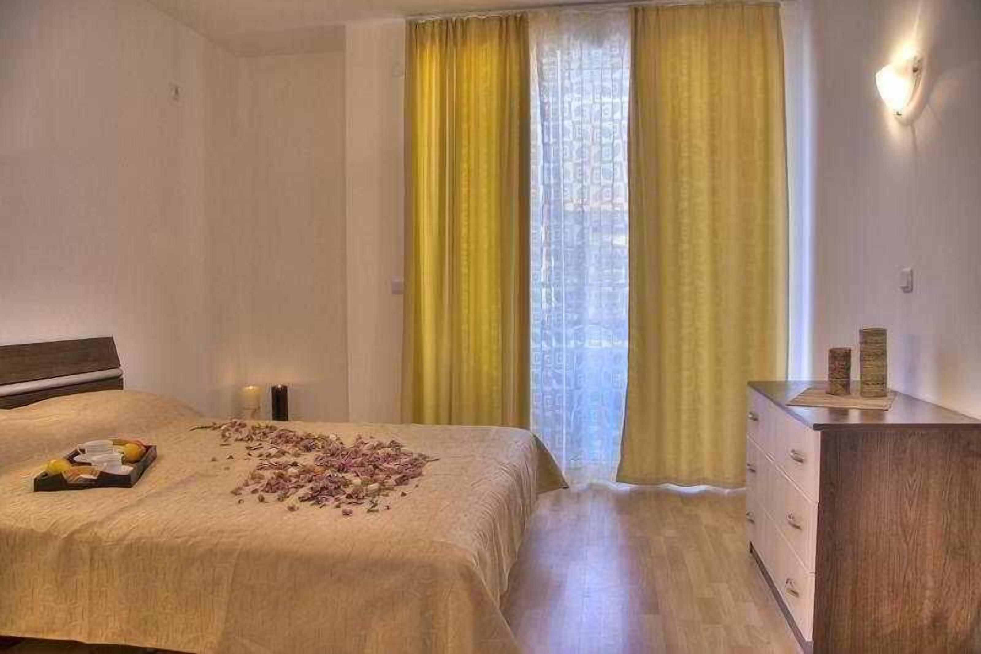 A hotel room with a bed, a dresser, and a window with yellow curtains.