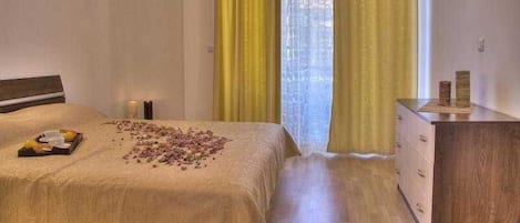 Une chambre d’hôtel avec un lit, une commode et une fenêtre avec des rideaux jaunes.