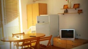 A compact kitchen with a refrigerator, a microwave, and a small dining table with chairs. - Laguna Holiday (Sunny Beach)