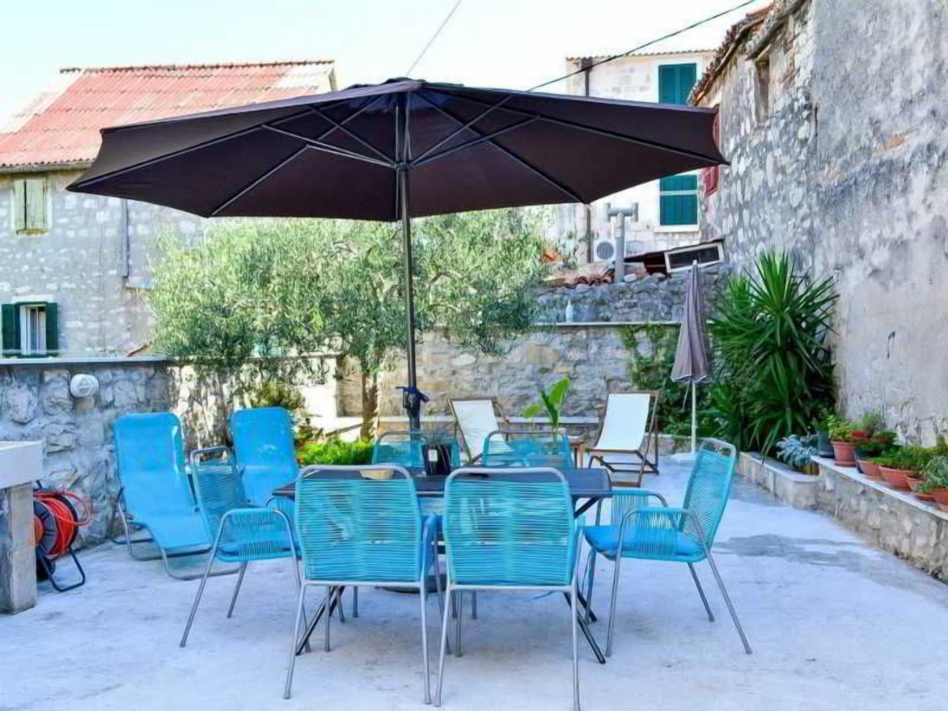 An outdoor patio with a table and chairs, a large umbrella, and a stone wall.