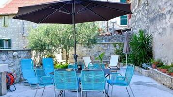 An outdoor patio with a table and chairs, a large umbrella, and a stone wall.
