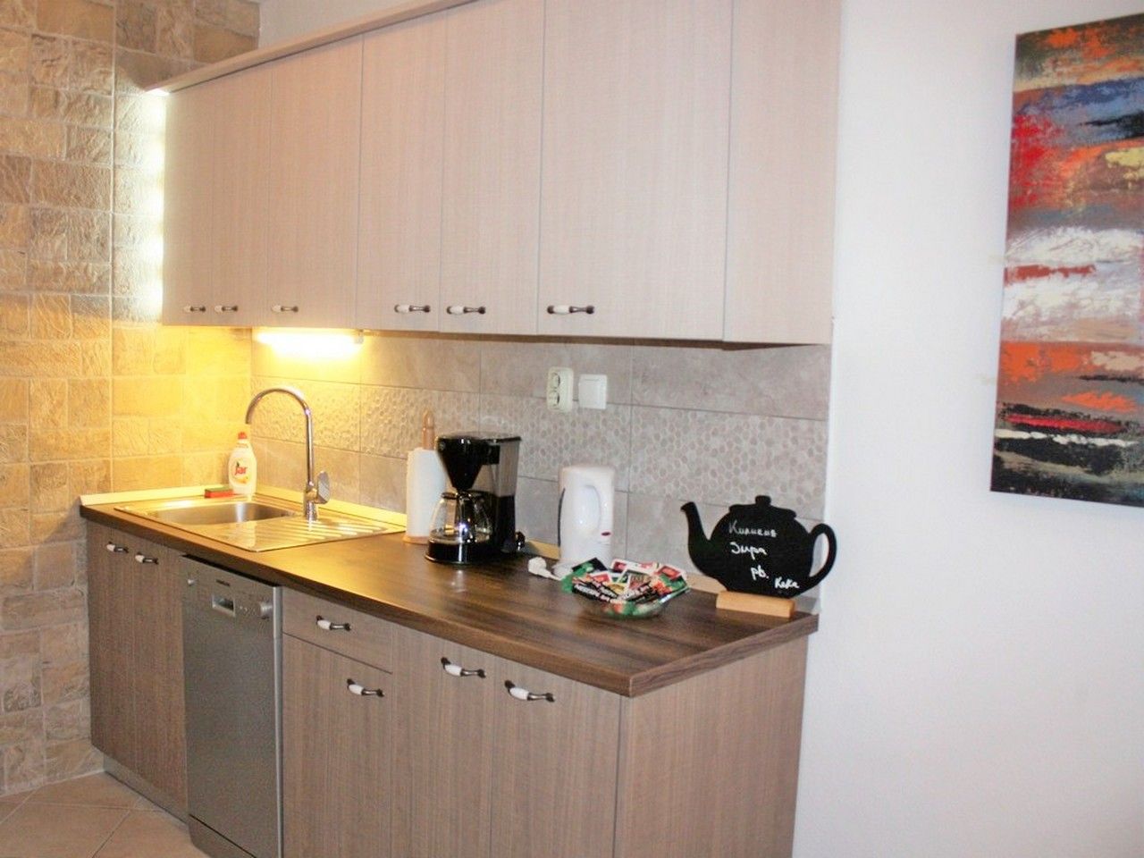 A compact kitchen with a sink, coffee maker, and tea pot.