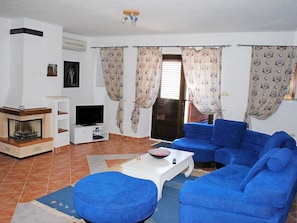 A living room with a fireplace, a TV, blue sofas, and patterned curtains. - Apartmani Slavica (Split)