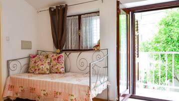 A bedroom with a metal bed frame, a window with curtains, and a view of greenery outside.