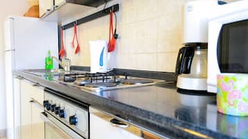 A kitchen with a stove, microwave, and coffee maker.