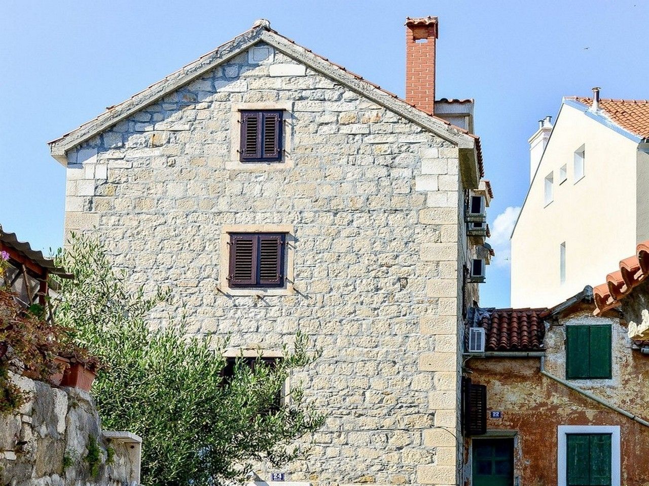 A stone building with two windows and a chimney.