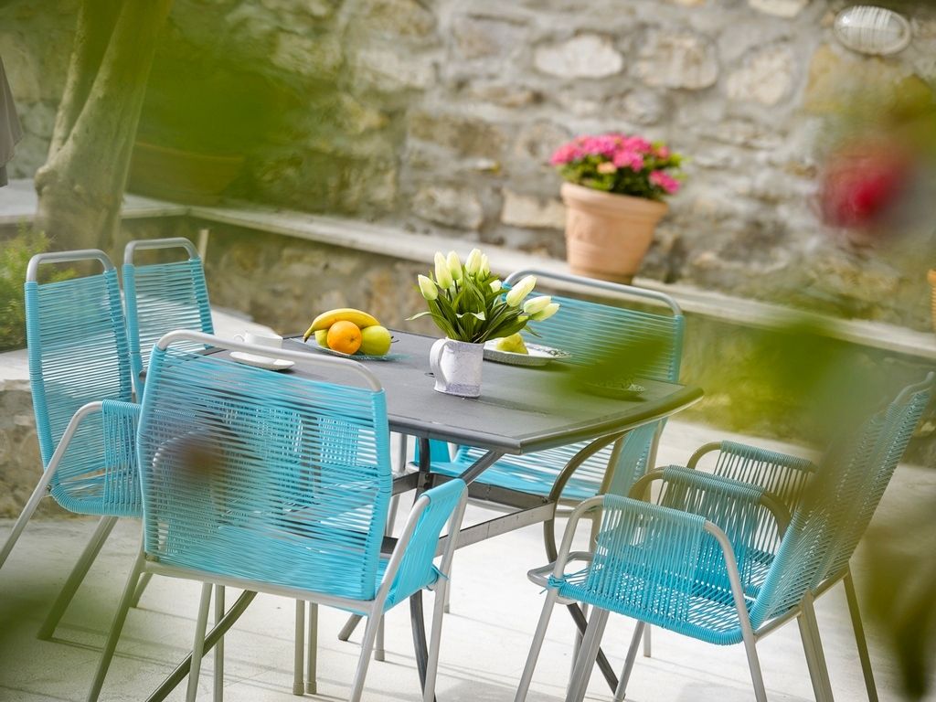 A table with chairs, a potted plant, and a fruit bowl.