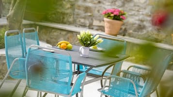 A table with chairs, a potted plant, and a fruit bowl.