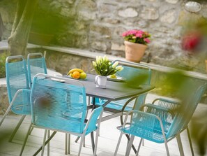 A table with chairs, a potted plant, and a fruit bowl.
