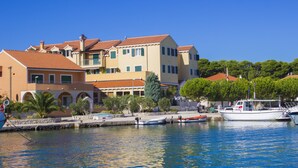 A waterfront property with a marina, featuring a multi-story building with balconies, a dock with boats, and a clear blue sky. - Hotel Spongiola (Sibenik)
