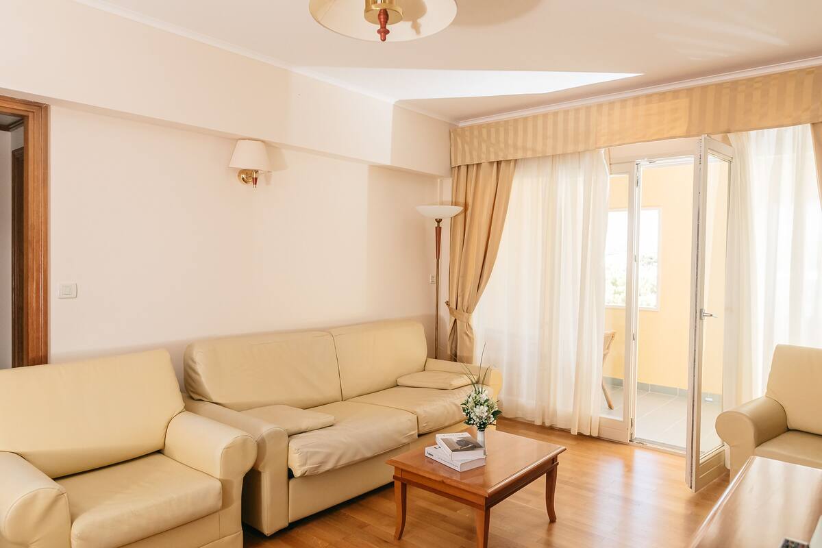 A living room with a beige sofa, a wooden coffee table, and a sliding glass door leading to an outdoor area.