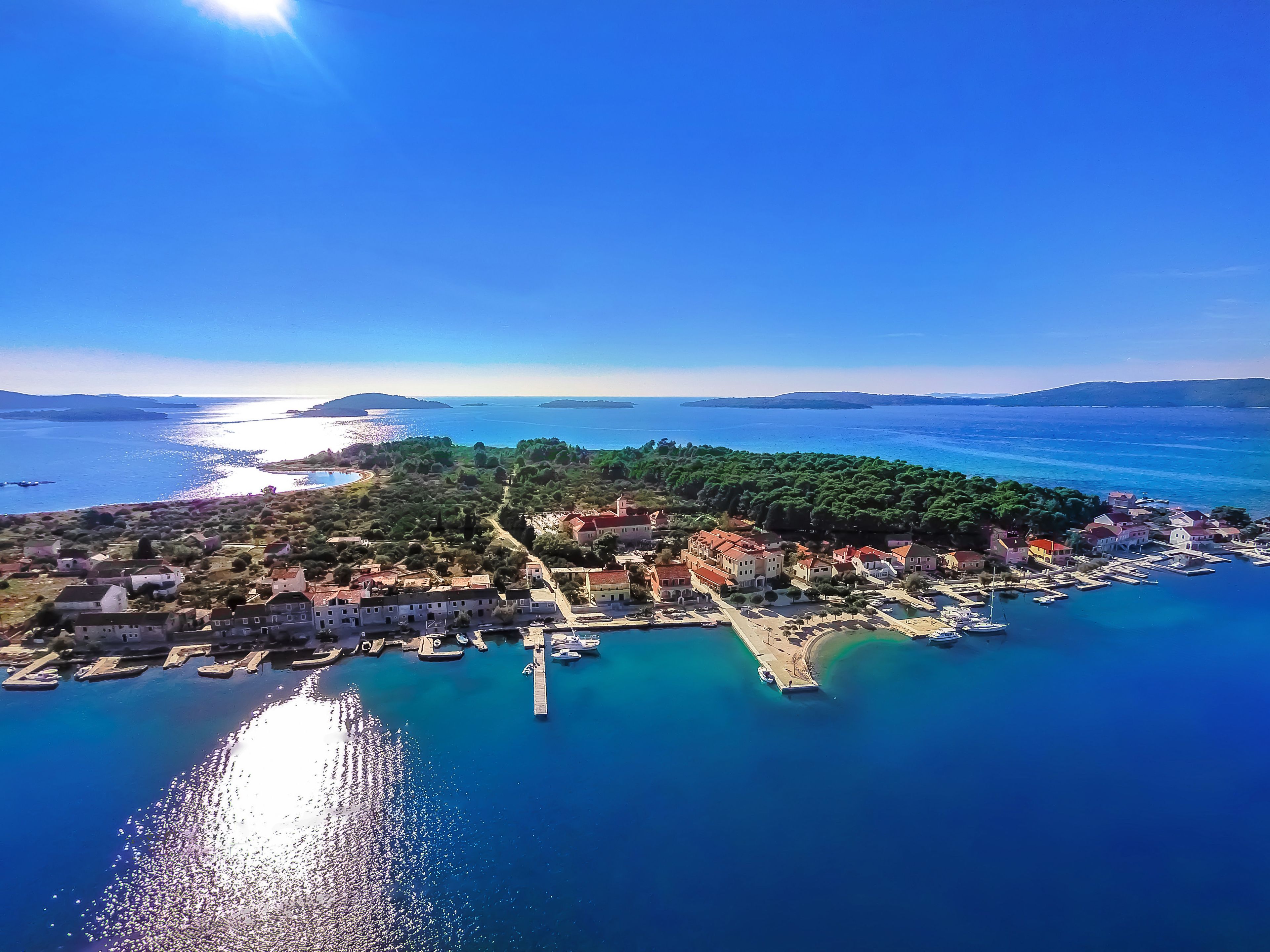 Vista aérea de un pueblo costero con edificios, muelles y aguas azul cristalino.