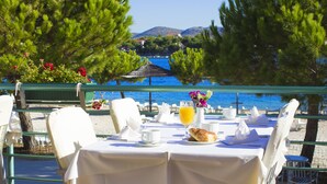 An outdoor dining area with tables set for breakfast, overlooking a body of water and hills. - Hotel Spongiola (Sibenik)