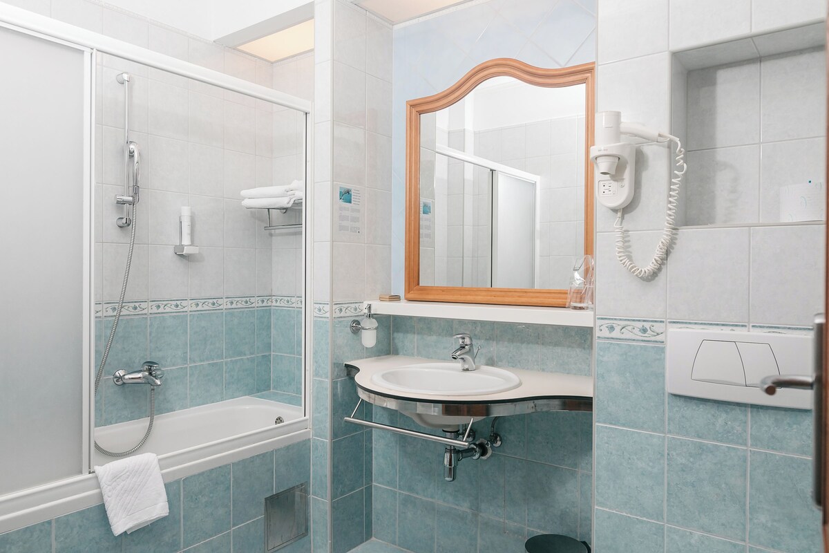 A bathroom with a shower, sink, and mirror.