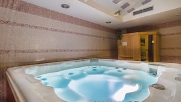 A hot tub with a control panel, surrounded by tiled walls and a wooden cabinet.