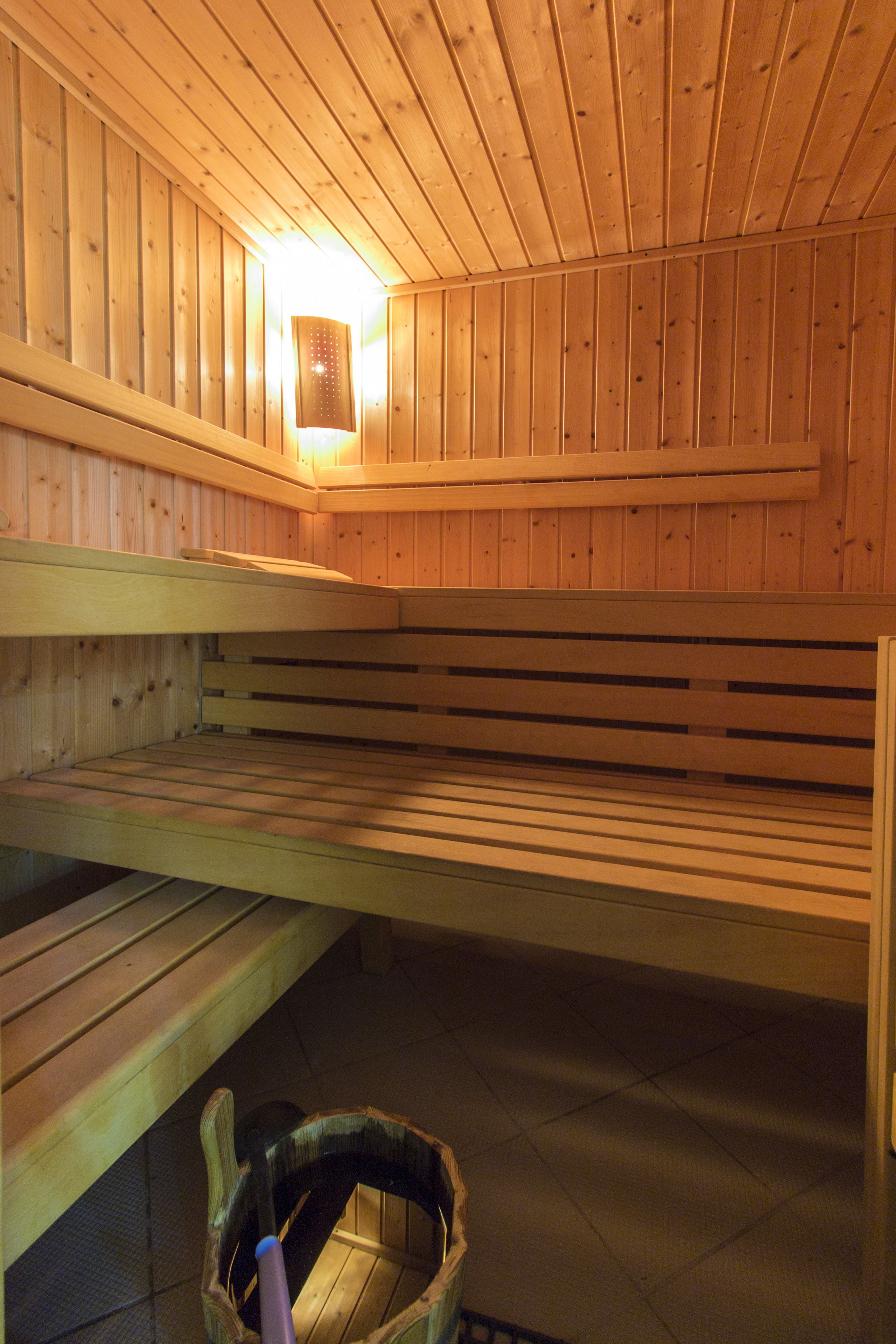 A sauna with wooden benches and a central light fixture.