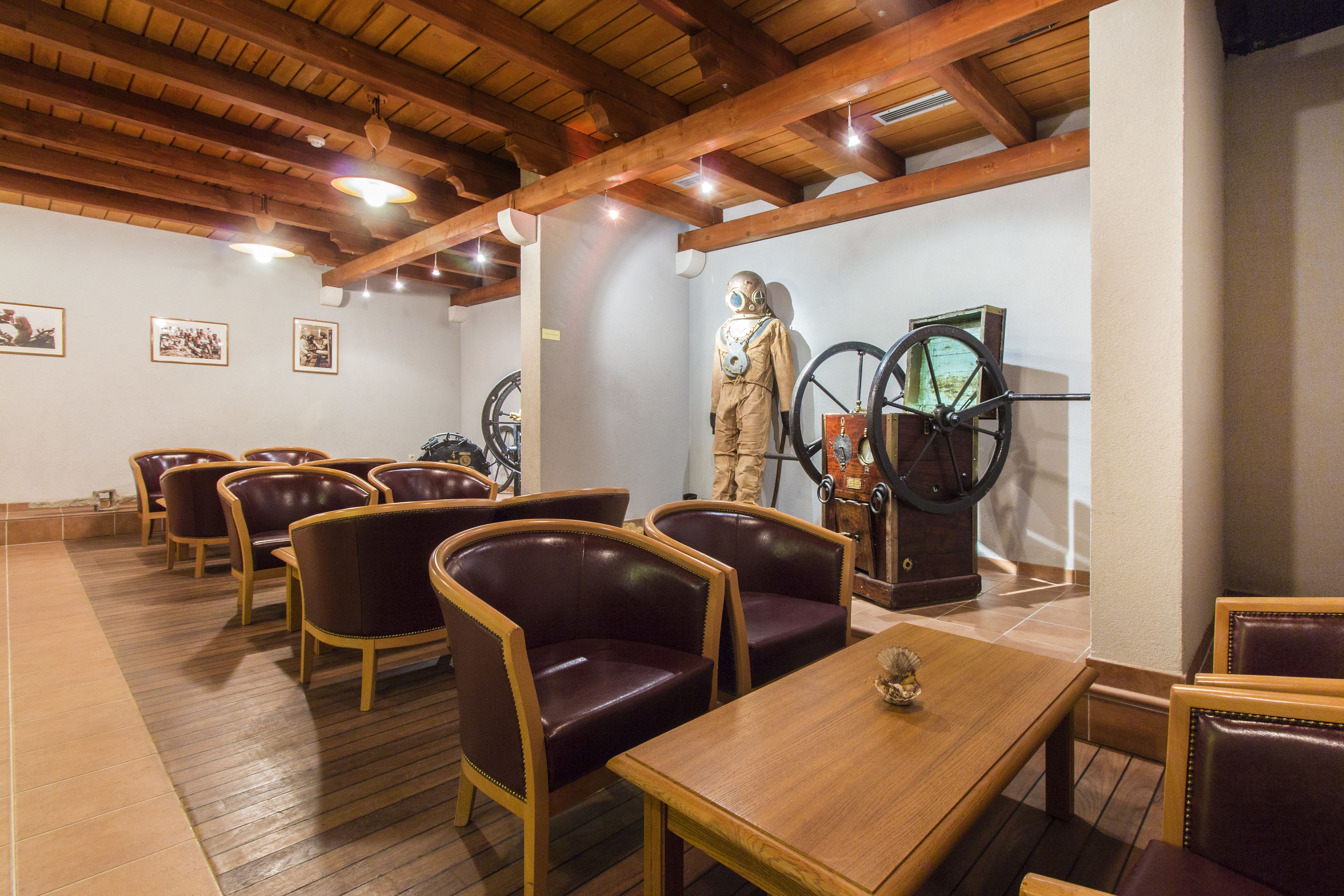 A restaurant with wooden tables and chairs, a large statue, and a bicycle wheel mounted on the wall.