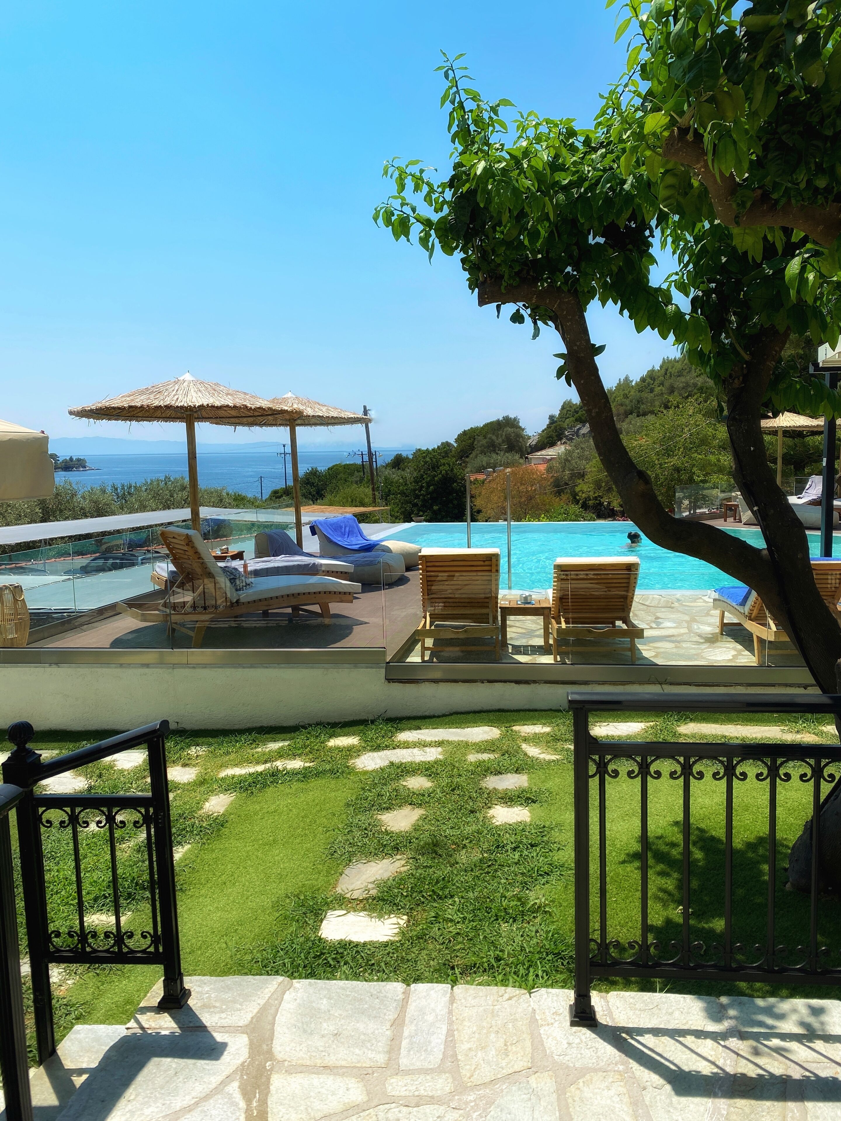 A pool area with lounge chairs and a view of the sea.