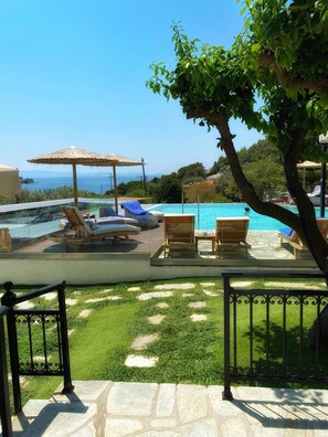 Un espace piscine avec des chaises longues et vue sur la mer.