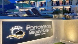 Een hotelschilt met een logo en de naam 'Panormos Beach Hotel'.