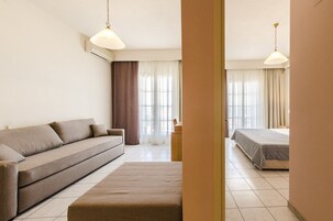 Habitación de hotel con sofá, cama, una mesita y dos lámparas colgantes.
